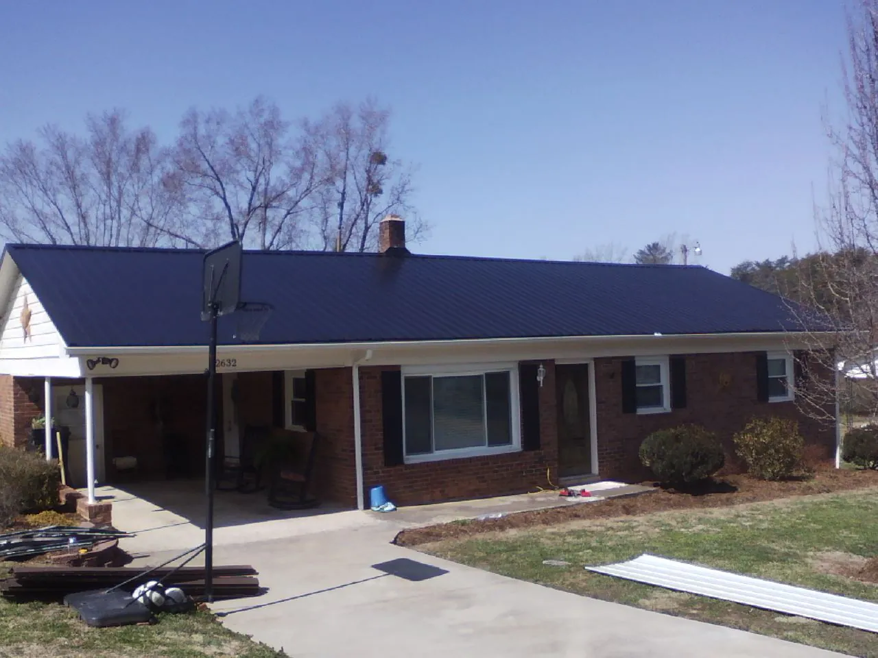 Finished dark blue metal roof on a brick ranch with a carport in Columbus